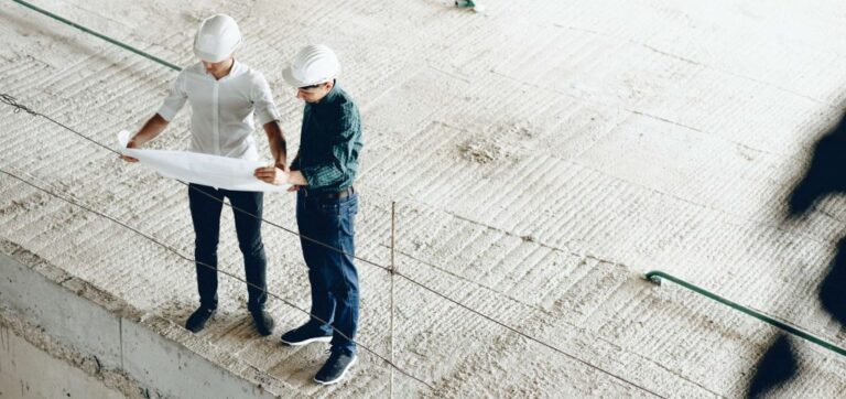 upper-view-portrait-two-engineers-looking-building-s-plan-while-holding-map-scaled-1-1024x482